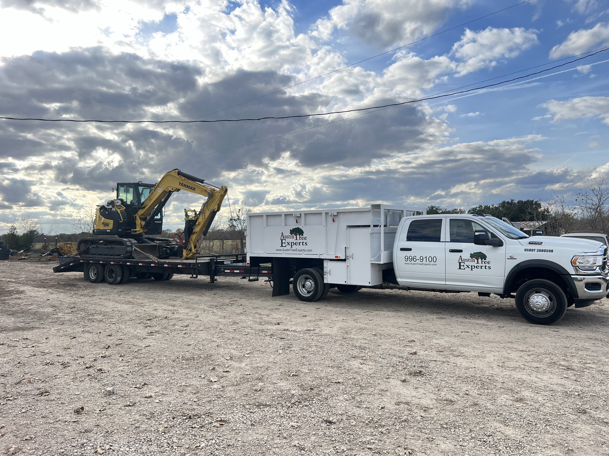 Excavator and equipment trailer staged for fuel break work near Austin