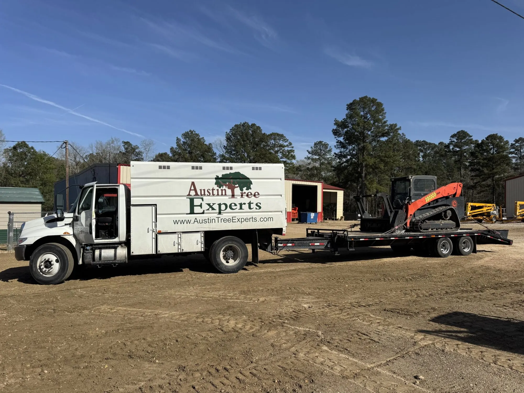 Austin Tree Experts truck with tracked mulching skid steer for fuel break work